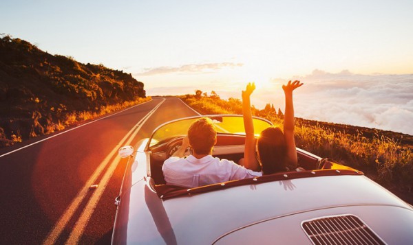Happy Couple Driving on Country Road into the Sunset in Classic Vintage Sports Car